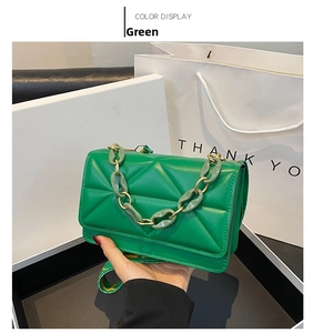 Detail of bright green quilted crossbody bag with gold and acrylic chain links