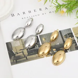 Lava style gold and silver liquid metal oval earrings on a minimalist magazine background