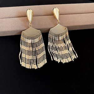 Detail of gold metal fan-shaped fringe earrings hanging on a jewelry display stand