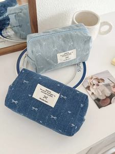 Detail of denim cosmetic bags with butterfly embroidery and soft zipper closure