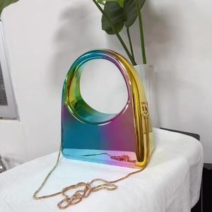 Macro detail of rainbow gradient acrylic clutch featuring gold chain and round handle