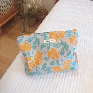 Detailed texture of jacquard fabric cosmetic bag with orange roses and teal leaves