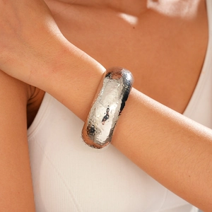 Detailed view of silver wide-open cuff bracelet with textured hammered metal pattern