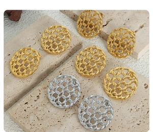 Close-up of gold and silver hollow woven earrings on a natural stone surface