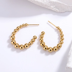 Detailed view of C-shaped golden beaded earrings with a polished gradient metallic finish