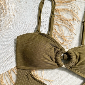 Détail d'un haut de bikini côtelé vert olive avec un anneau central décoratif blanc