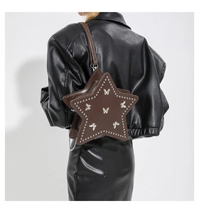 Detail view of a star-shaped brown studded crossbody bag worn by a model in leather outfit