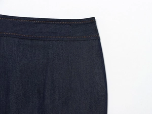 Détail de la taille en denim bleu marine avec doubles coutures orange et texture