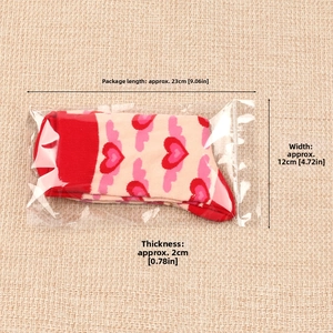Detail of pink cotton socks with red heart patterns in transparent sealed packaging