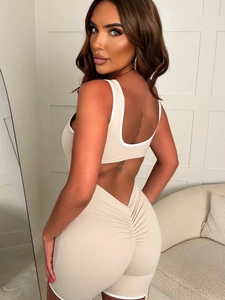 Beige Y2K sports romper with white trim, open back cutout, and ruched butt detail