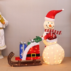 Close-up of lighted Christmas snowman with red sleigh and gift boxes for holiday decor