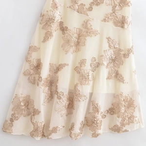 Détail de broderie florale champagne sur tulle blanc cassé pour une robe de soirée élégante