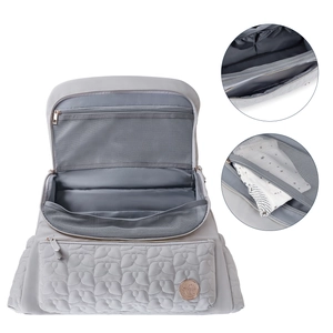 Detailed interior of gray quilted diaper bag showing multi-layer storage and mesh pockets