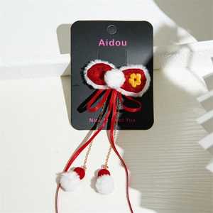 Detail of red plush hair clip with white faux fur tassels and golden chain accents