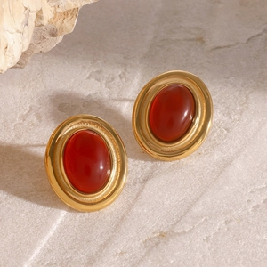 Detail of vintage oval red agate earrings with brushed gold frames on stone background