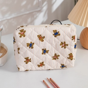 Quilted makeup bag with brown bear pattern and metal zipper in a cozy home setting