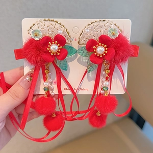 Close-up of red tassel hair clips with pom-poms, golden fans, and green leaf charms