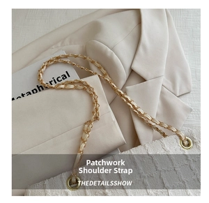 Detail of cream shoulder bag featuring metal chain and leather interwoven strap