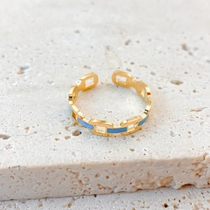 Macro shot of gold-plated hollow chain ring with sky blue enamel on stone surface