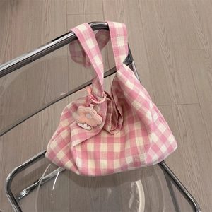 Detailed view of pink and white checkered canvas tote bag with floral charm on a chair