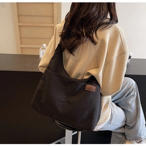Model wearing a black large capacity canvas tote bag with a minimalist fashion leather label
