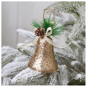 Gros plan d'une cloche de Noël dorée pailletée sur une branche de pin enneigée avec nœud
