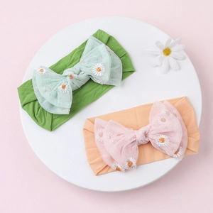 Detailed view of baby headbands with tulle bows and embroidered daisy patterns