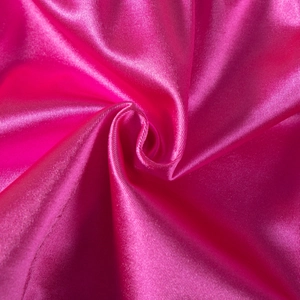Macro shot of bright pink satin fabric showing glossy texture and drape of sports shorts