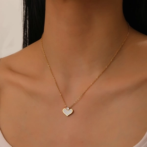 Close-up of gold chain necklace with white shell heart pendant on model's neck