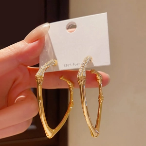 Detail of gold bamboo hoop earrings with S925 silver post and sparkling white zircons