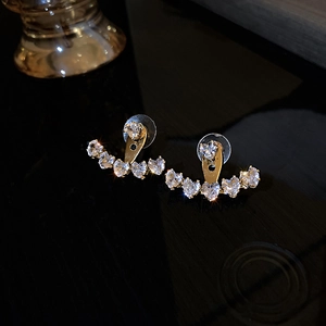 Detail shot of heart-shaped zircon earrings in gold finish on a black background