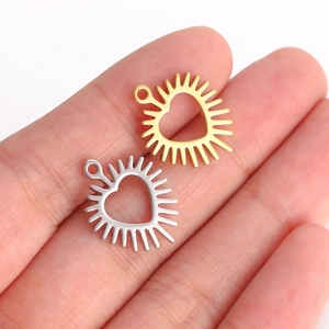 Golden and silver heart pendants with sunray edges displayed on a palm for size scale