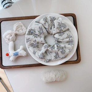 Detailed view of a light floral print cotton scrunchie on a decorative white plate
