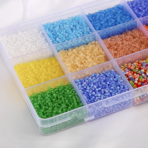 Macro shot of assorted colorful glass seed beads in a transparent plastic organizer box