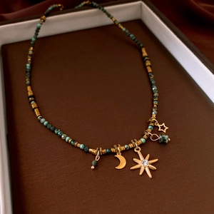 Detail of star, moon, and sun pendants on turquoise beaded necklace with gold spacers