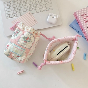 Detailed macro view of quilted floral drawstring storage bag for instant camera