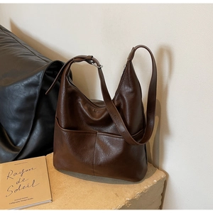 Detail of a brown vintage leather hobo bag featuring an adjustable strap and external pocket