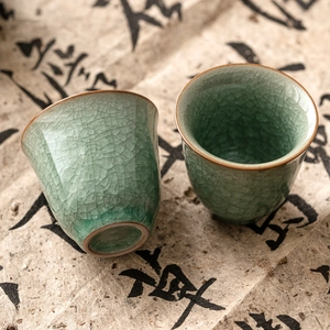 Ru-kiln ice crack ceramic teacups set on vintage calligraphy paper background