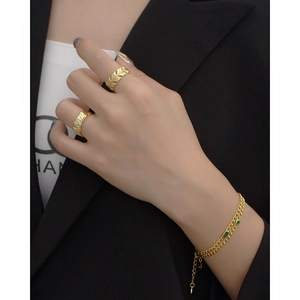 Close-up of gold textured rings and a green gemstone bracelet on a model's hand