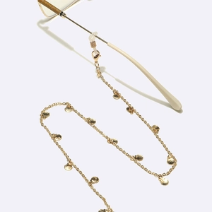 Close-up of golden metal eyewear chain with detailed shell pendants on white background