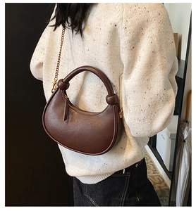 Detailed macro view of dark brown leather hobo bag with gold chain and metal zipper