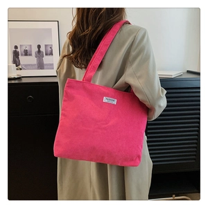 Detail of pink corduroy tote bag showing soft ribbed texture and fashion logo patch