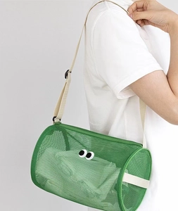 Green mesh beach bag with eye patch design shown as a shoulder bag on a model