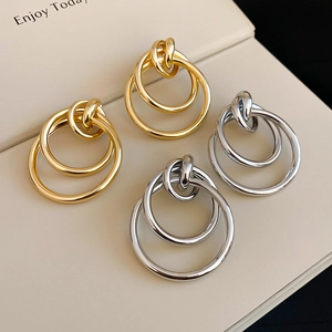 Détails de boucles d'oreilles créoles triples entrelacées en or et argent au fini brillant