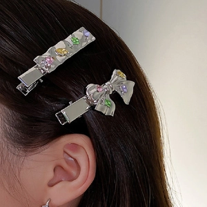 Close-up of a silver bow hair clip and gemstone bar pin worn on model's hair