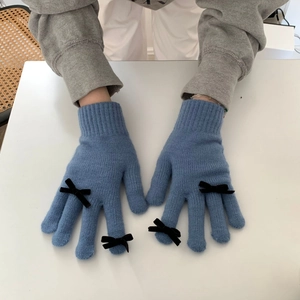 Blue knit gloves with black bow accents shown being worn over a grey sweater sleeve