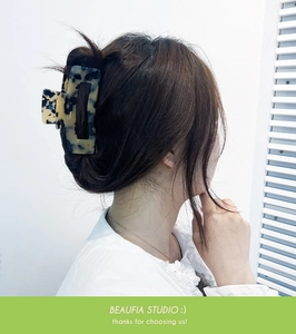 Detail view of large tortoiseshell acetate claw clip securing hair in a low bun style