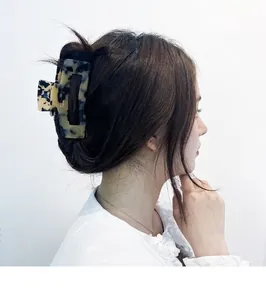 Detail view of large tortoiseshell acetate claw clip securing hair in a low bun style