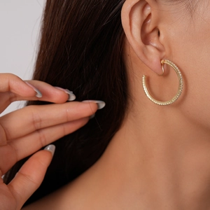 Close-up of a gold-plated C-shaped hoop earring with sparkling rhinestones on model