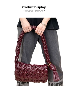 Close-up of burgundy woven leather shoulder bag featuring tassel knots and brass rings